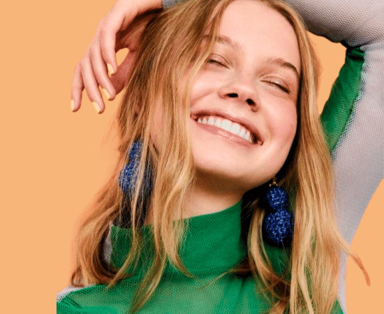 lachende vrouw met groen shirt en blauwe oorbellen.